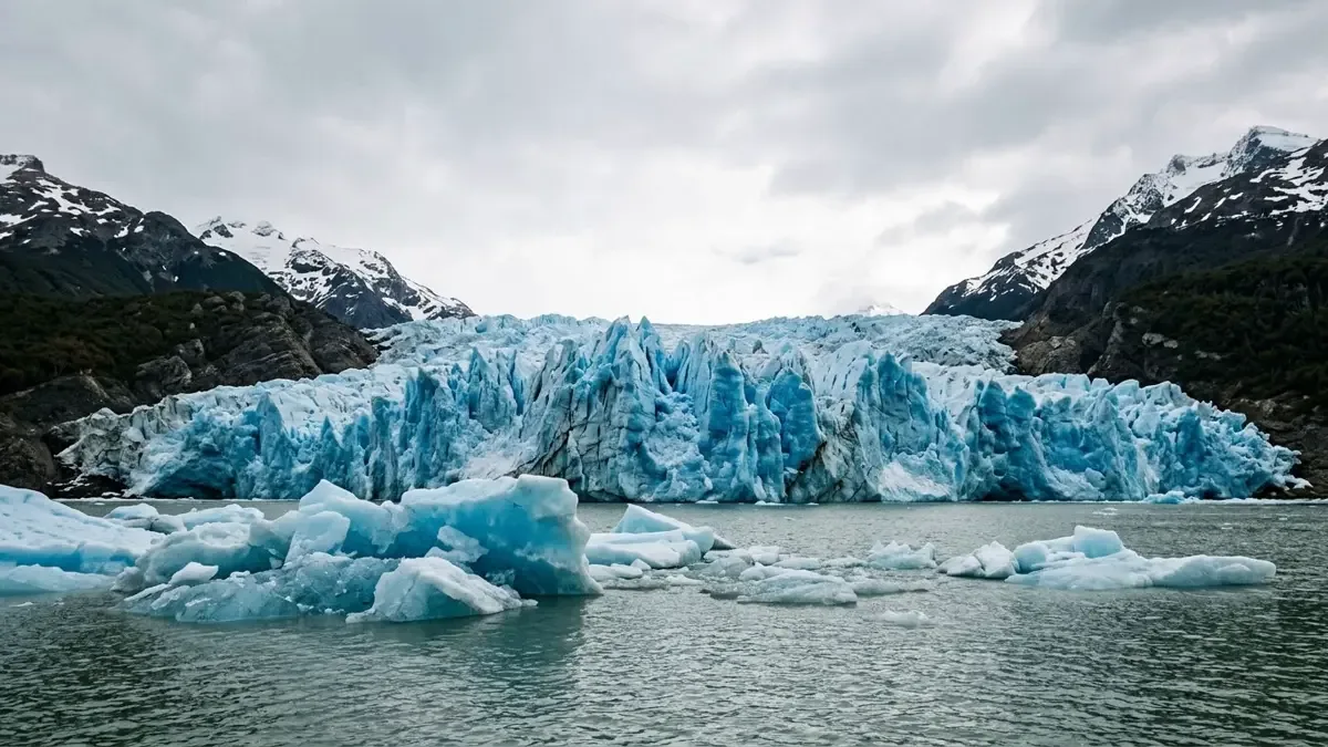 Frente de un glaciar patagónico con pared de hielo azul fracturado y témpanos en el agua