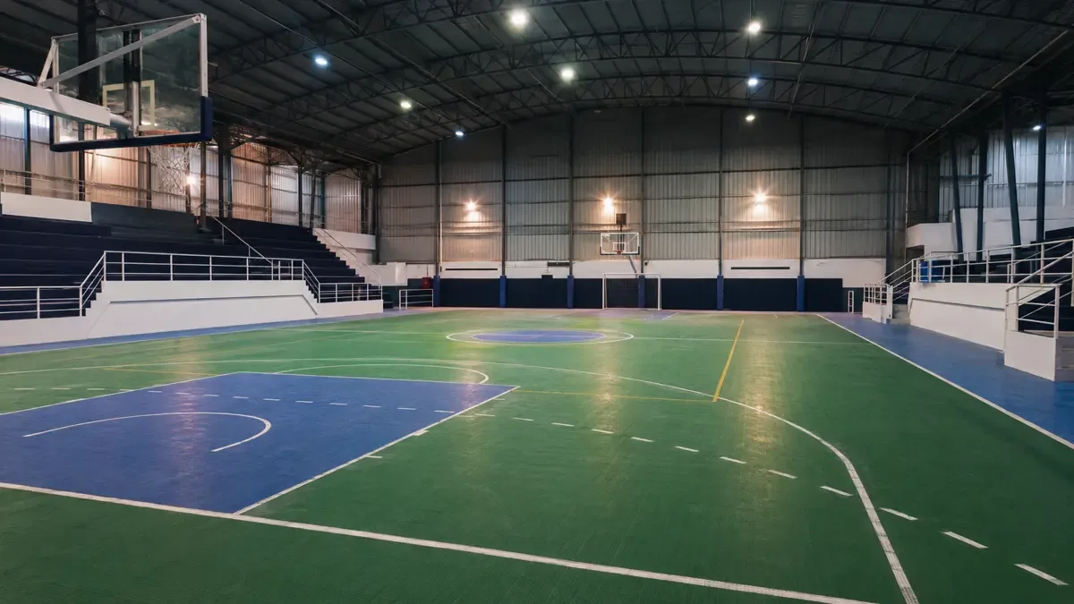Interior de un gimnasio cubierto con cancha vacía y tribunas laterales
