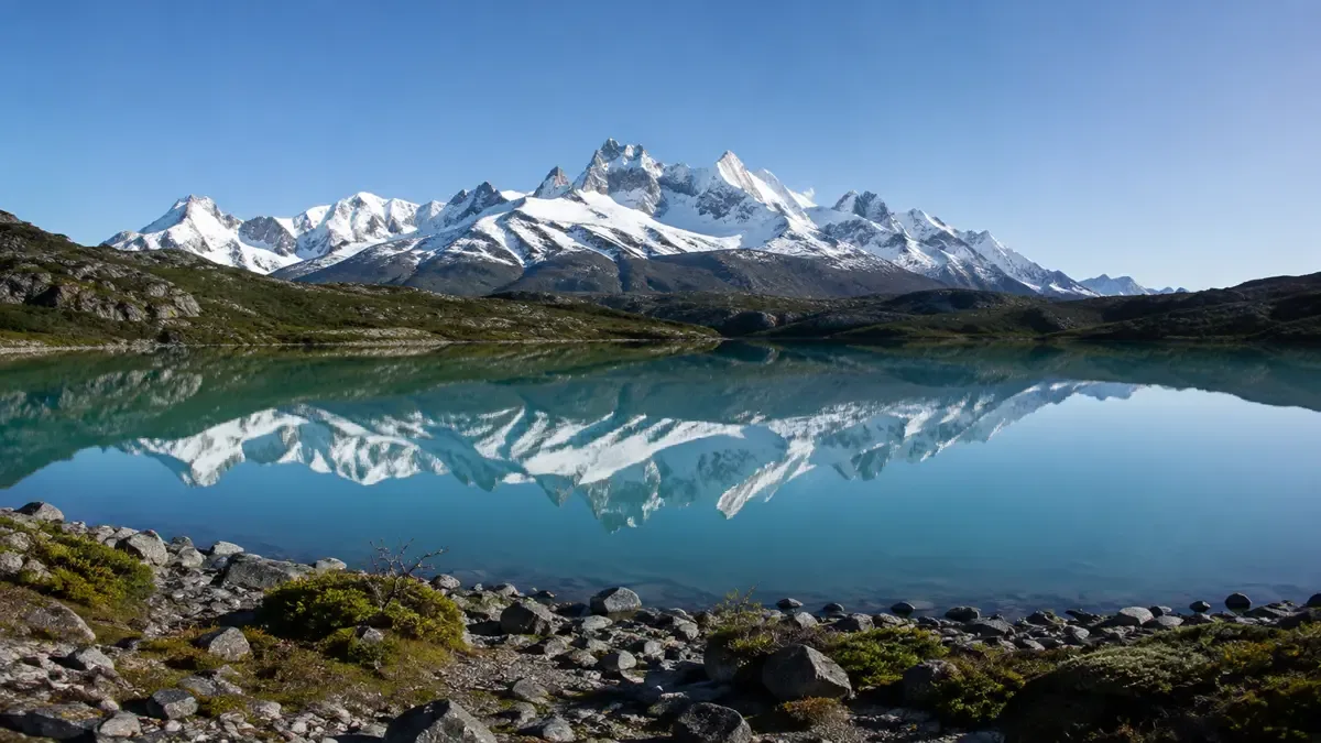 Lago turquesa con picos nevados de la cordillera patagónica reflejados en el agua