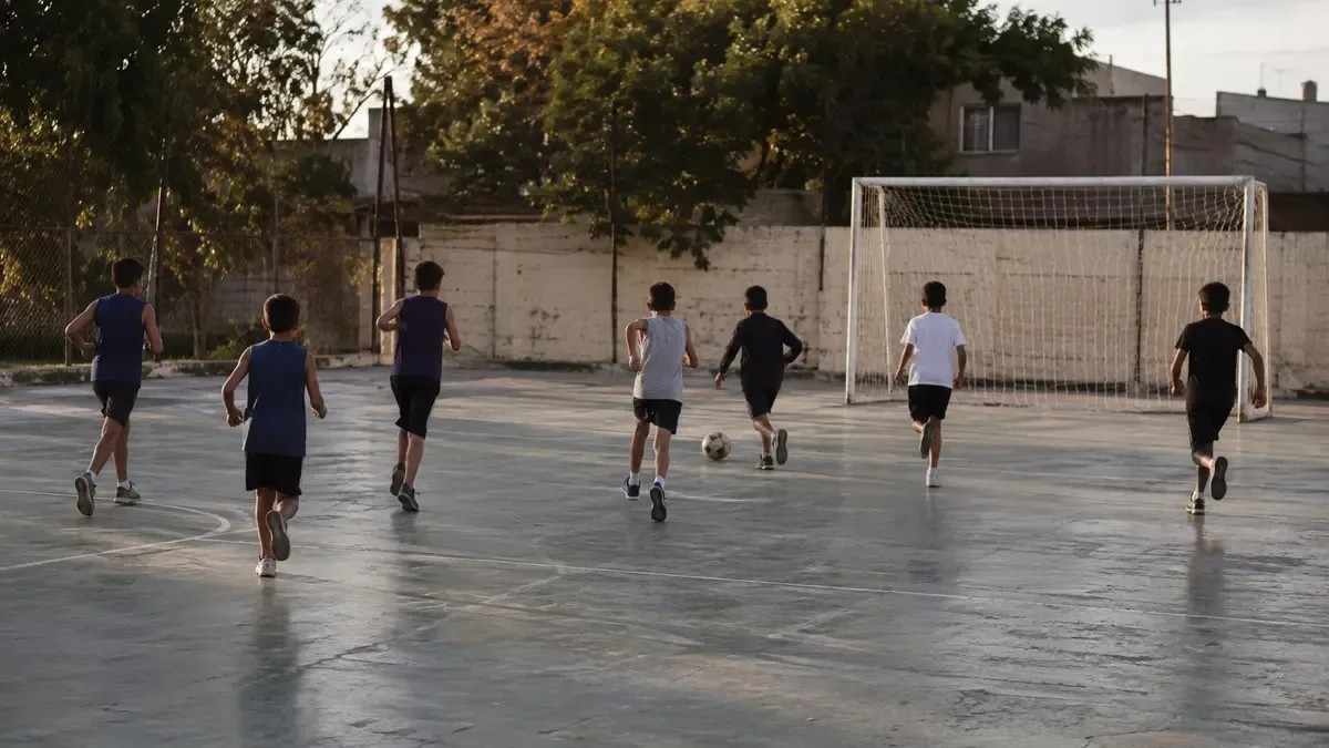Chicos practicando deporte en el patio de un club de barrio.
